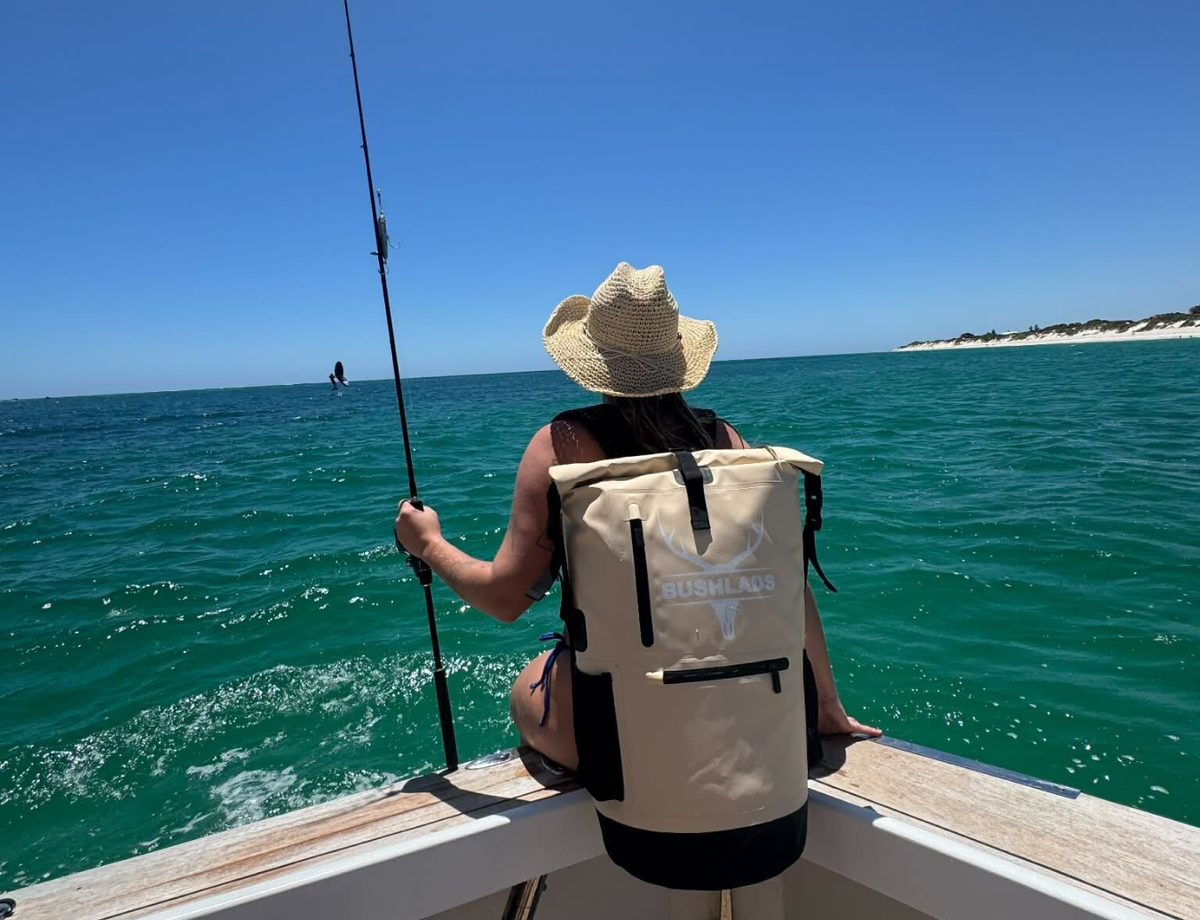Angler holding a catch while wearing the Bushlads 35L backpack