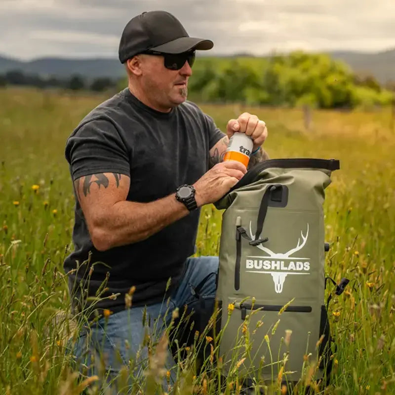 Man reaching into the Bushlads pack in long grass at sunset