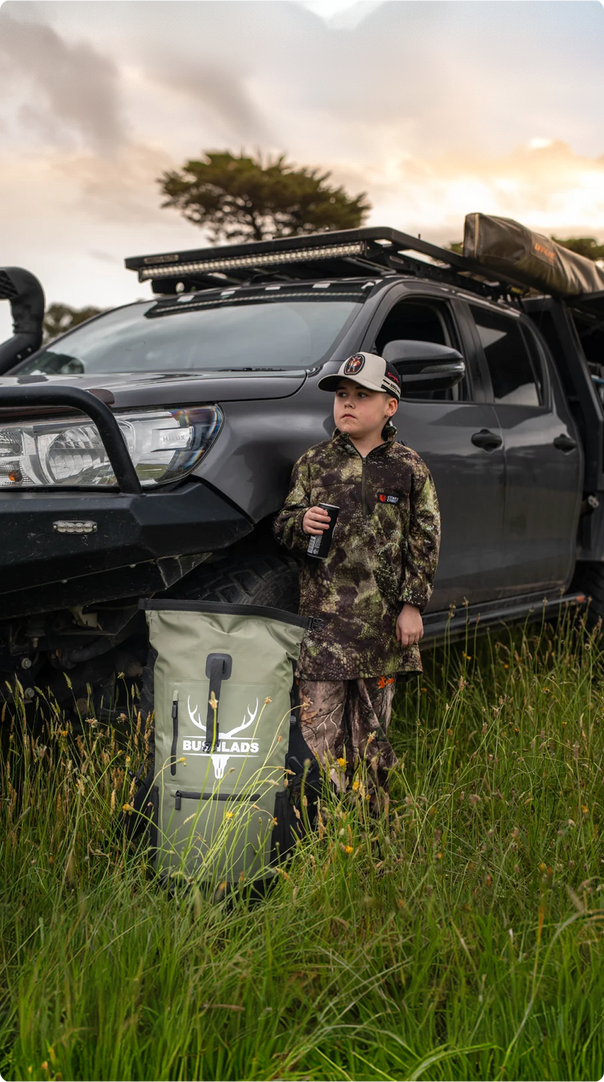 Hunter beside a 4WD at dusk with the Bushlads pack on the ground
