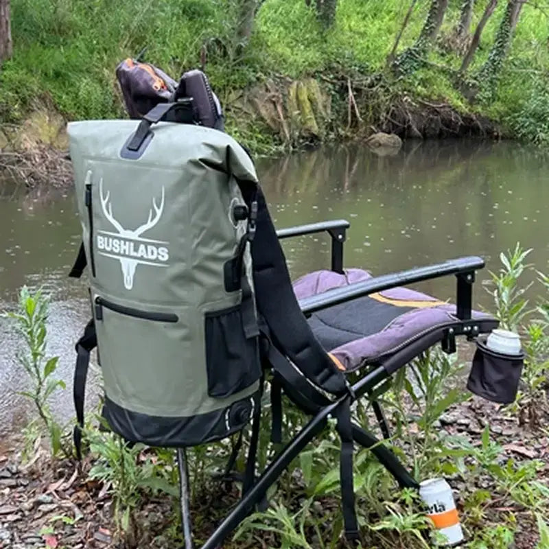 Man setting up camp chairs beside a creek with the Bushlads pack