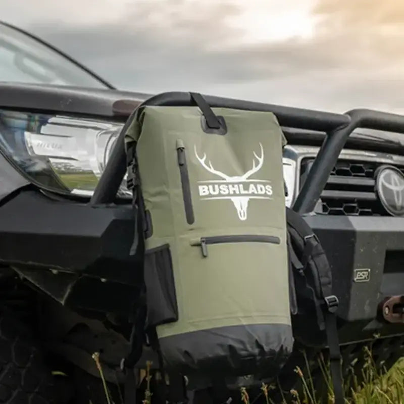 Hunter beside a 4WD at dusk with the Bushlads pack on the ground