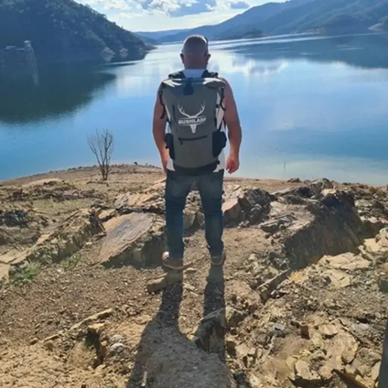 Man standing on a clifftop above a lake wearing the Bushlads 35L backpack